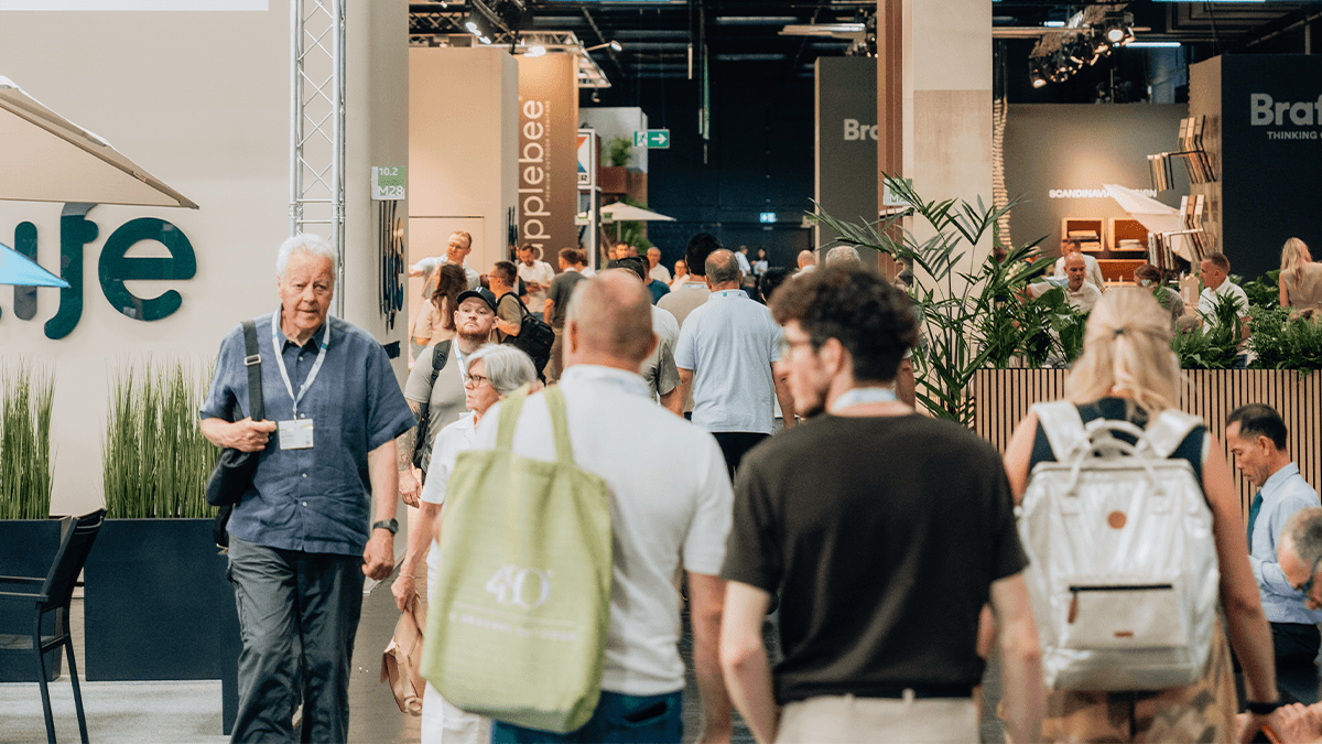 spoga+gafa 2026 Tag 3 04 Eine geschäftige Indoor-Veranstaltung mit Teilnehmern, die an Ständen, Pflanzen und Beschilderungen vorbeigehen, die Produkte und Anbieter präsentieren.